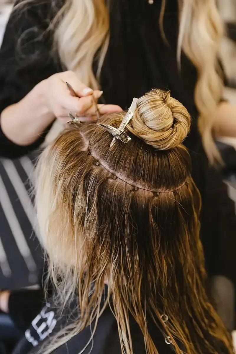 A certified stylist installing an NBR beaded row of hand-tied extensions